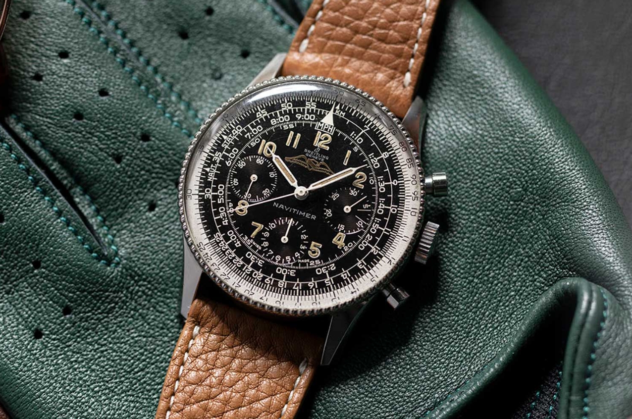 Navitimer style chronograph with brown leather strap against a green background