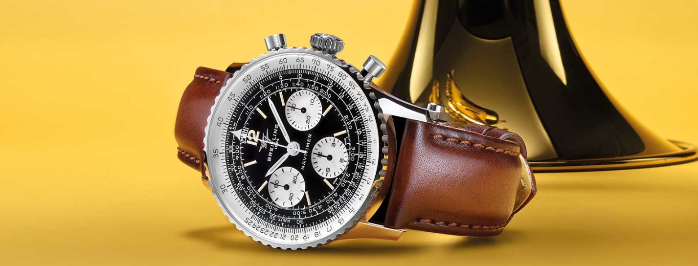 Breitling Navitimer B09 style chronograph with brown strap beside a trumpet
